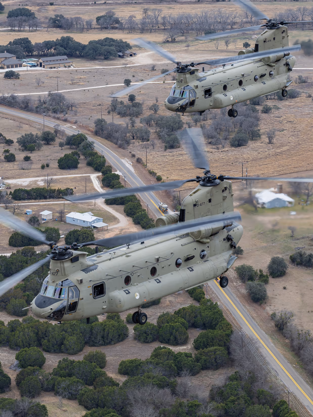 Twee Chinooks van bovenaf vliegend over Texaans landschap.