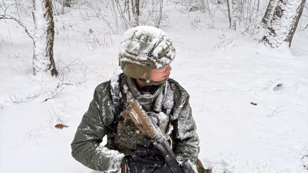 Marechaussee met lang wapen in de sneeuw.