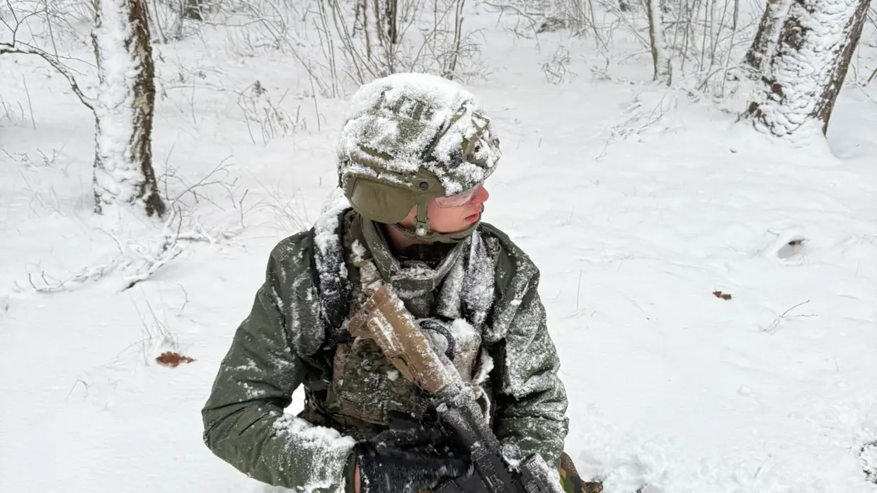 Marechaussee met lang wapen in de sneeuw.