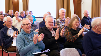 Heren en dames applaudiseren in een zaal.