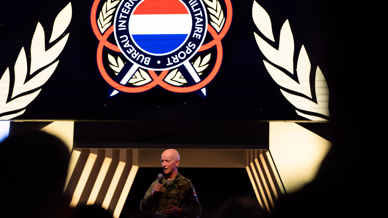 Brigadegeneraal Laurens Jobse achter een spreekgestoelte met een spandoek op de achtergrond.