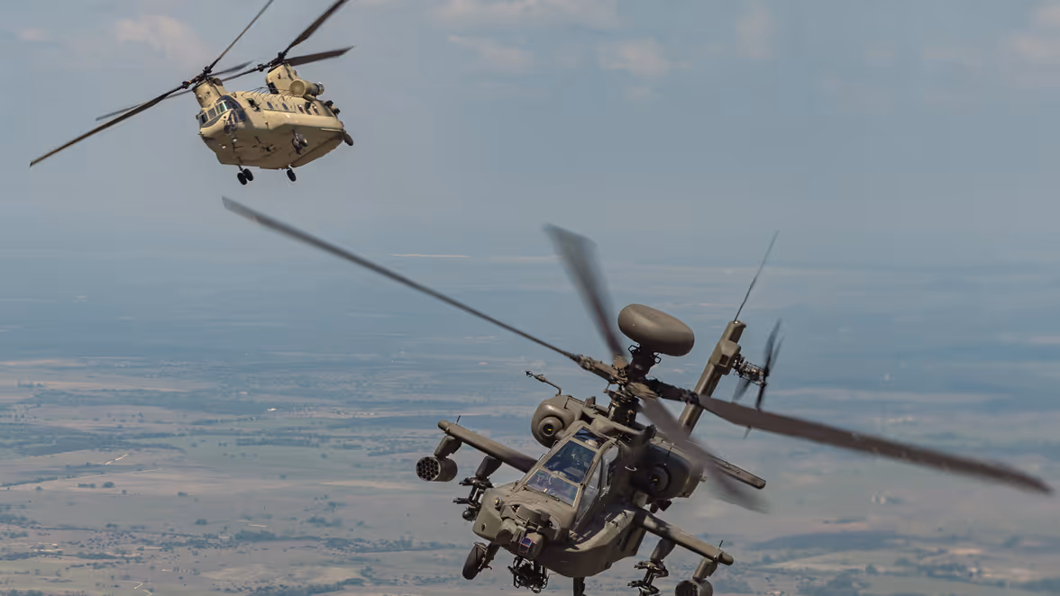 Een Chinook en Apache vliegend over Texaans landschap. 