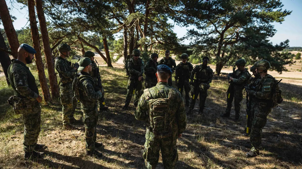 een groep marechaussees tijdens instructie in het bos. 