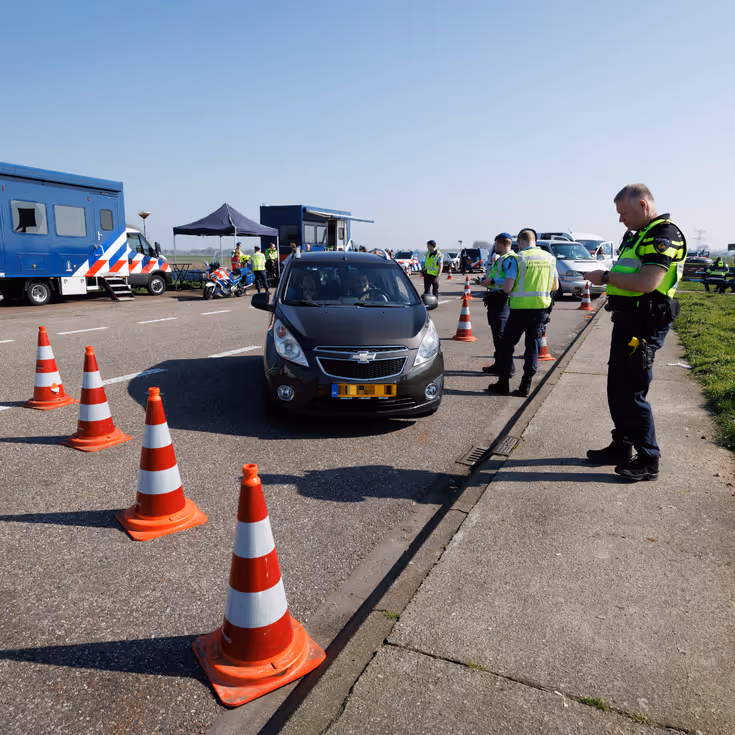 Politie en Marechaussee tijdens een controle op een parkeerplaats.