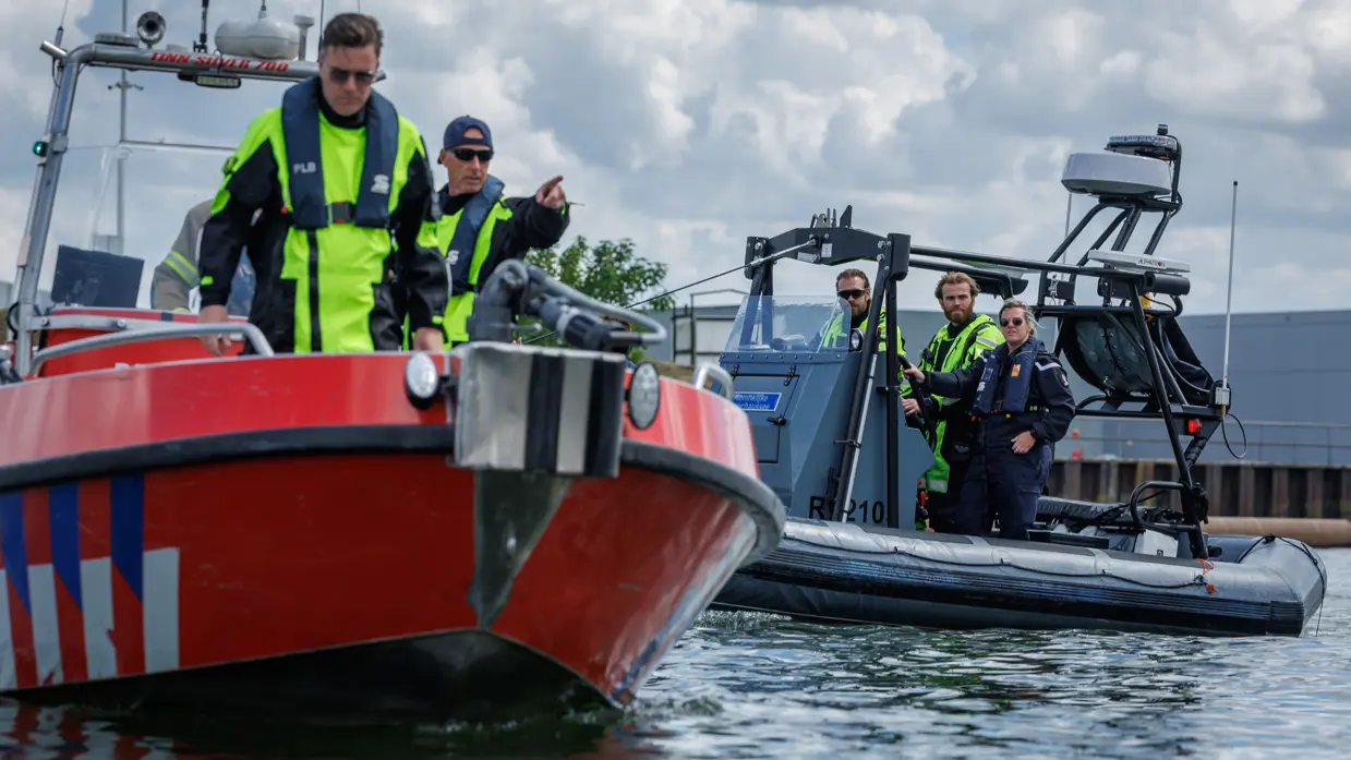 Vaartuig van de brandweer met op de achtergrond een vaartuig van de Marechaussee.