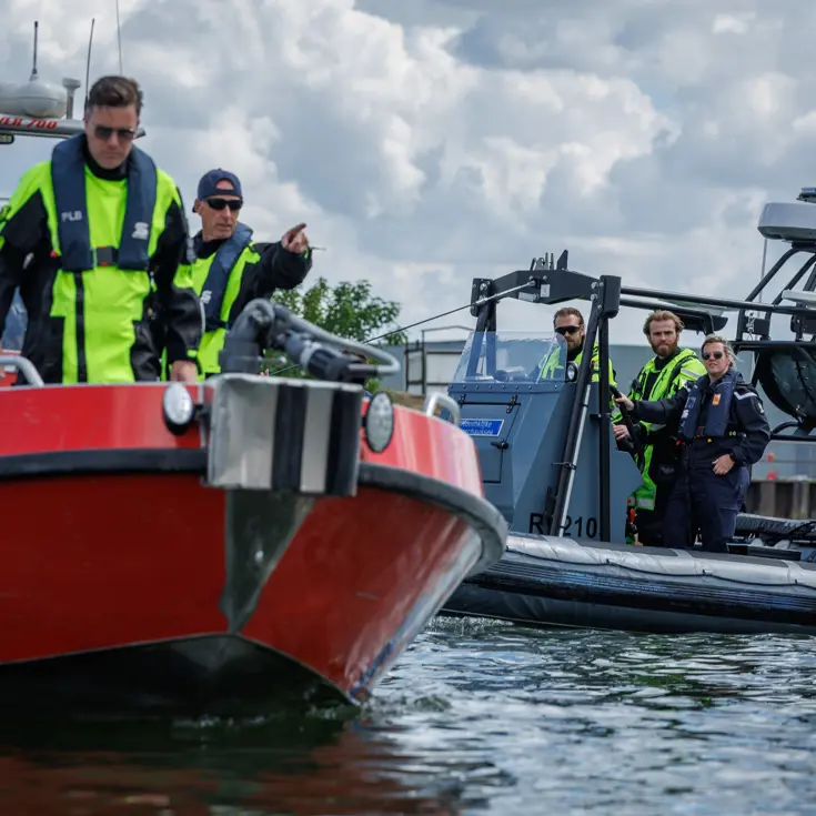 Vaartuig van de brandweer met op de achtergrond een vaartuig van de Marechaussee.