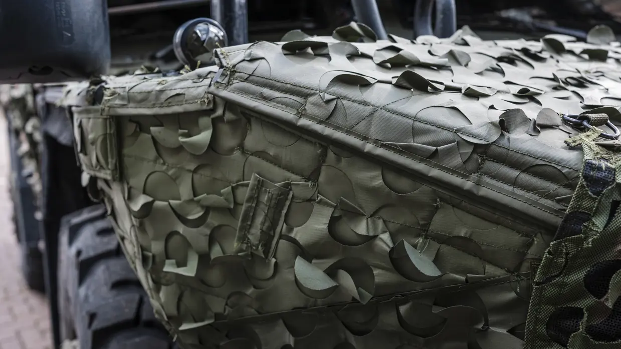 Een militair voertuig met daarop een camouflagesysteem.