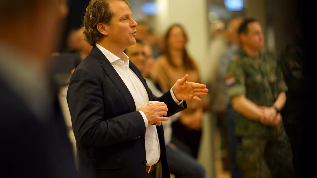 Staatssecretaris Gijs Tuinman spreekt een groep mensen toe en gebruikt daarbij zijn handen.