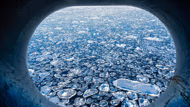 Afbeeldingen van het ‘pannenkoekijs’ waar het schip doorheen vaart. Dit zijn kleine ijscirkels die in de zee drijven. Ook een foto van het schip dat door het ijswater vaart en een klein bootje dat over de zee scheurt.