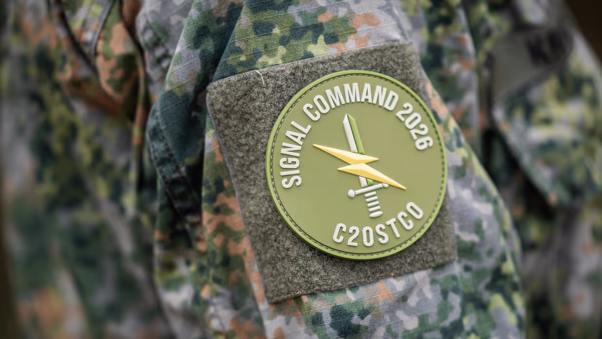Een lichtgroene patch op de arm van een militair, met daarop de naam van de oefening ‘Signal Command’, daaronder een zwaard met een bliksemschicht en daaronder C2OstCo, wat staat voor Command and Control Ondersteuningscommando. 