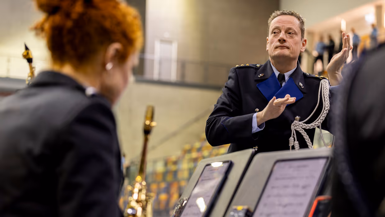 Dirigent van het KMar-orkest, Ido Gerard Kempenaar, in actie tijdens de beëdiging van het OTCKMar in een sporthal in Apeldoorn.