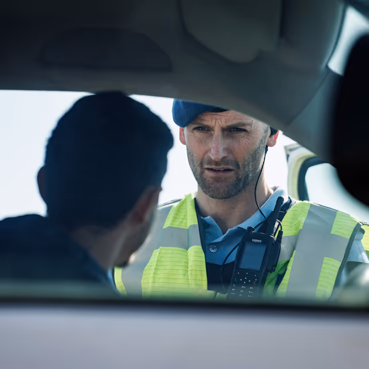  Een marechaussee praat door het raam van een auto met een bestuurder.