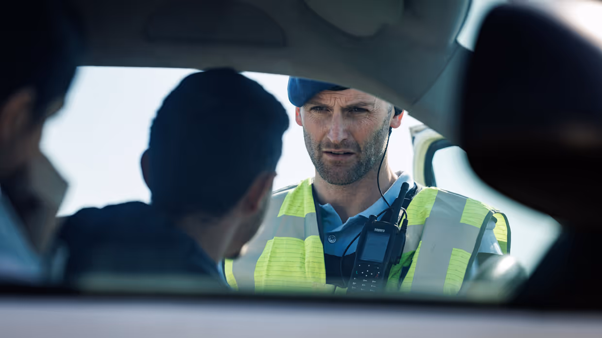  Een marechaussee praat door het raam van een auto met een bestuurder.