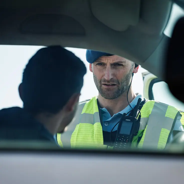  Een marechaussee praat door het raam van een auto met een bestuurder.