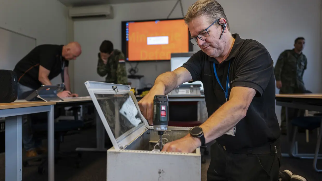  Een ICT-medewerker monteert apparatuur in een mobiele netwerkkast tijdens de opbouw voor Falcon Leap.