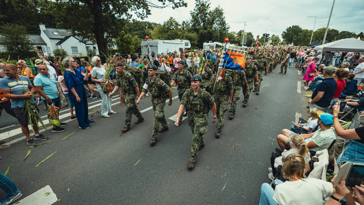 Het ASC-detachement loopt midden over de weg langs het publiek dat aan weerszijden staat.