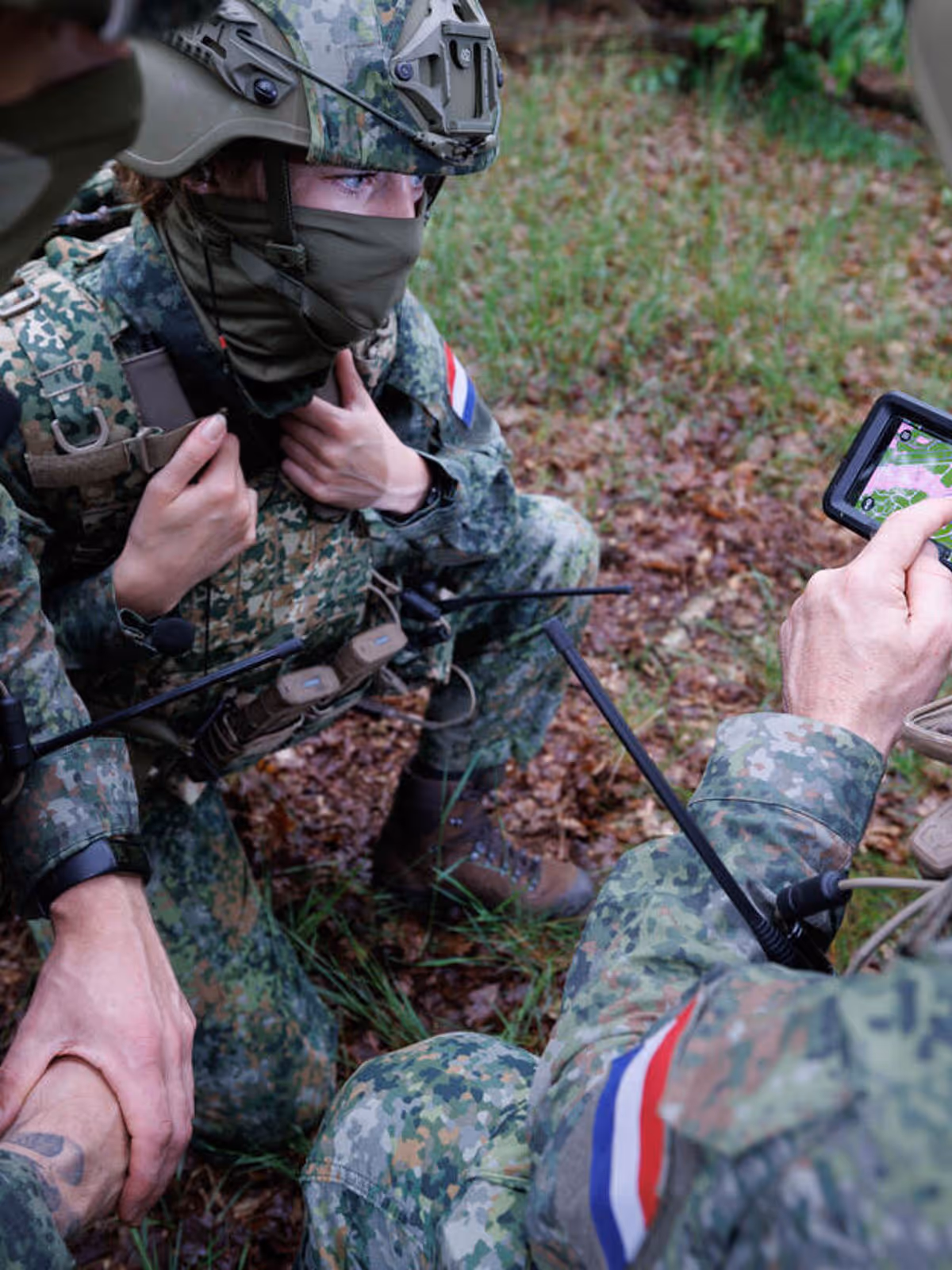 Militairen wijzen naar een kaartje op een telefoonscherm.