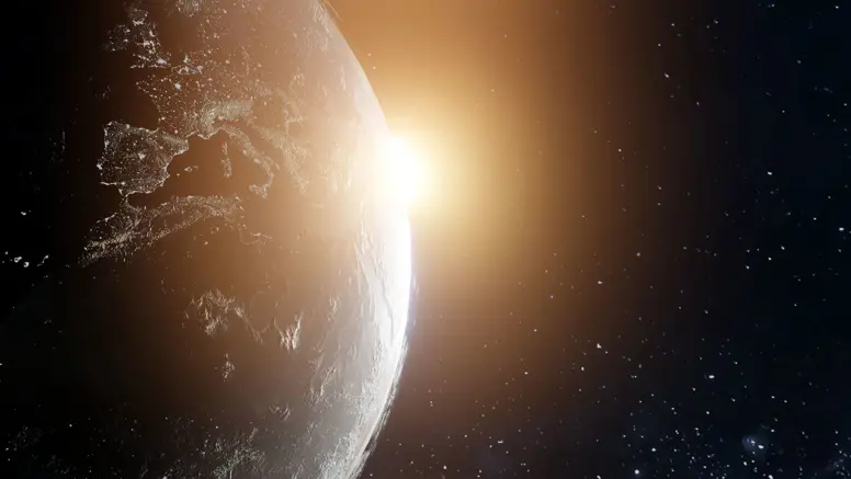 Een wereldbol. Daarachter komt de zon tevoorschijn.