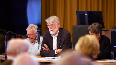 Een aantal statige mensen achter een lange tafel.