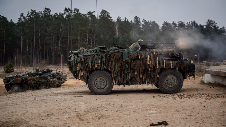 Militairen schieten vanuit een Fennek-voertuig.
