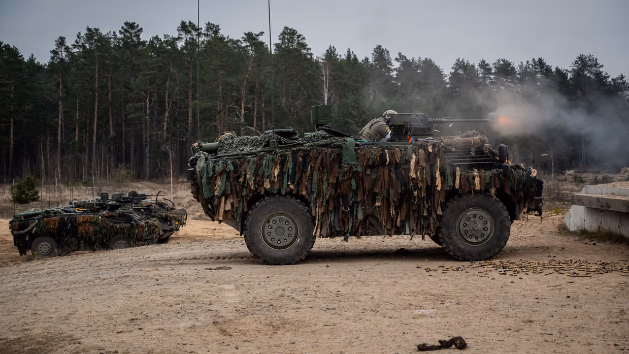 Militairen schieten vanuit een Fennek-voertuig.