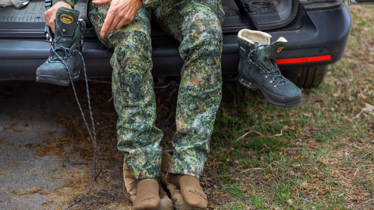 Links: iemand trekt een groene bergschoen aan met een zwarte beugel, buiten op een bosbodem met bladeren.    Midden: Iemand in camouflagebroek zit op een auto met bruine sokken en houdt een groene bergschoen vast. Rechts: Een man in uniform houdt een metertje vast. 