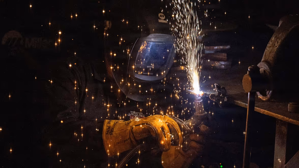 Een straaljager vliegt ondersteboven hoog in de lucht en trekt een witte rooklijn achter zich aan, tegen een lichte, heldere hemel.    