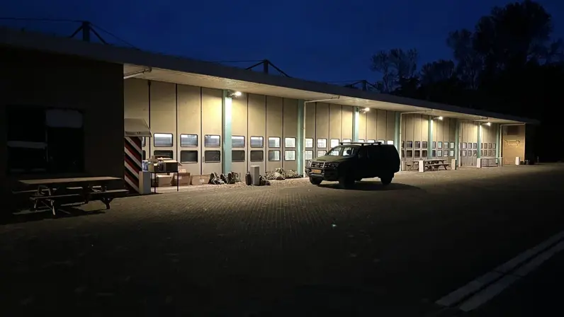 Alttekst: Een militair voertuig staat in het donker geparkeerd voor een loods. 
