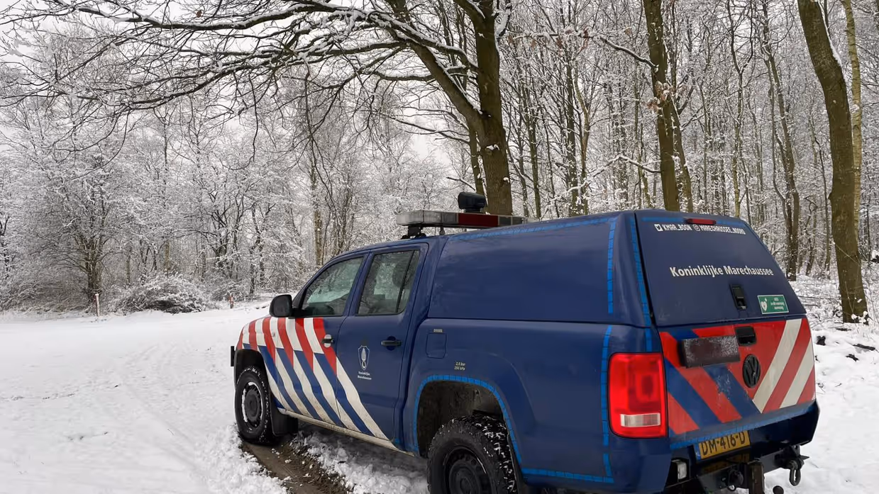 Voertuig van de Marechaussee in een besneeuwd bos.