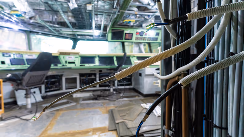 Losliggende kabels en open consoles in de commandocentrale van Zr.Ms. Holland tijdens onderhoudswerkzaamheden.