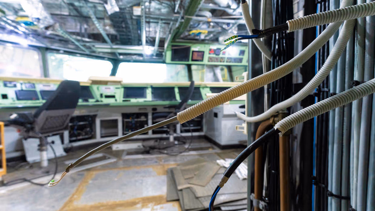 Losliggende kabels en open consoles in de commandocentrale van Zr.Ms. Holland tijdens onderhoudswerkzaamheden.