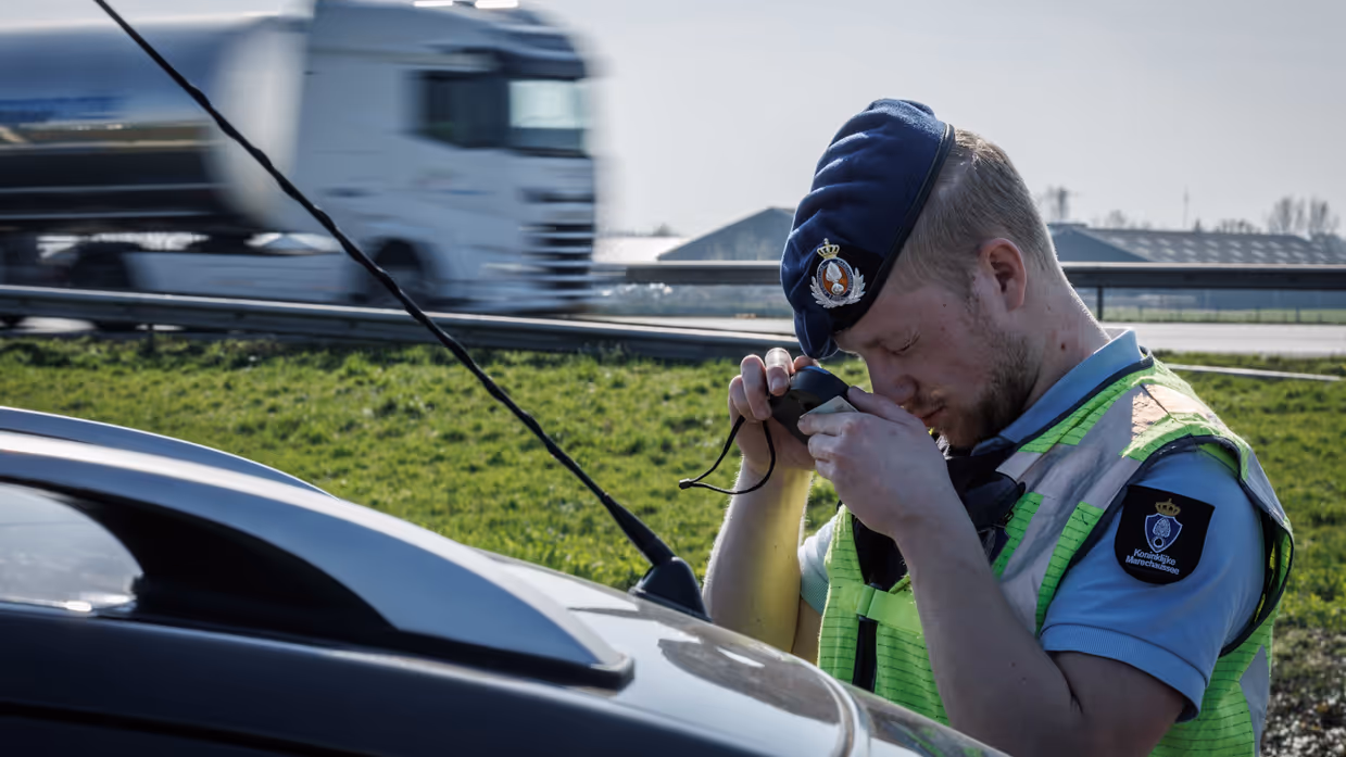 Een marechaussee bestudeert door een loep een identiteitsdocument.