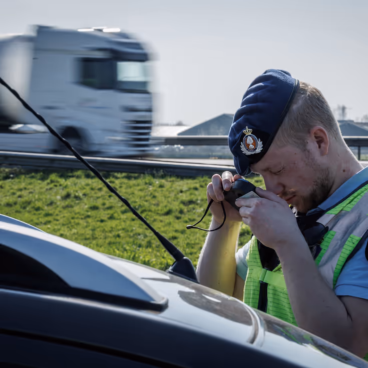 Een marechaussee bestudeert door een loep een identiteitsdocument.