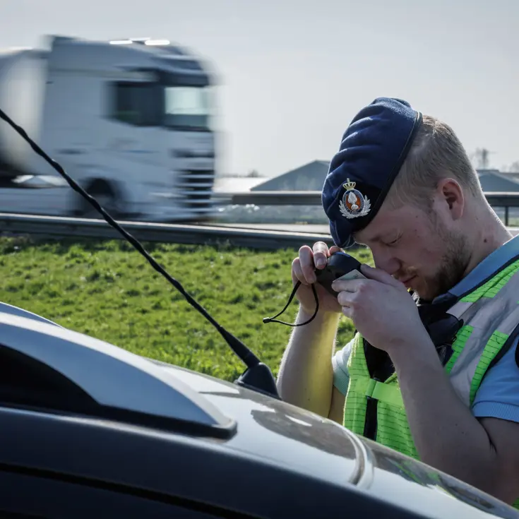 Een marechaussee bestudeert door een loep een identiteitsdocument.