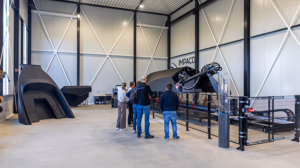  Vijf mensen kijken in fabriekshal naar de 3D-geprinte boot.