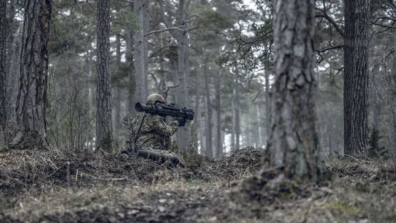 Militairen in het bos met een wapen op de schouder.