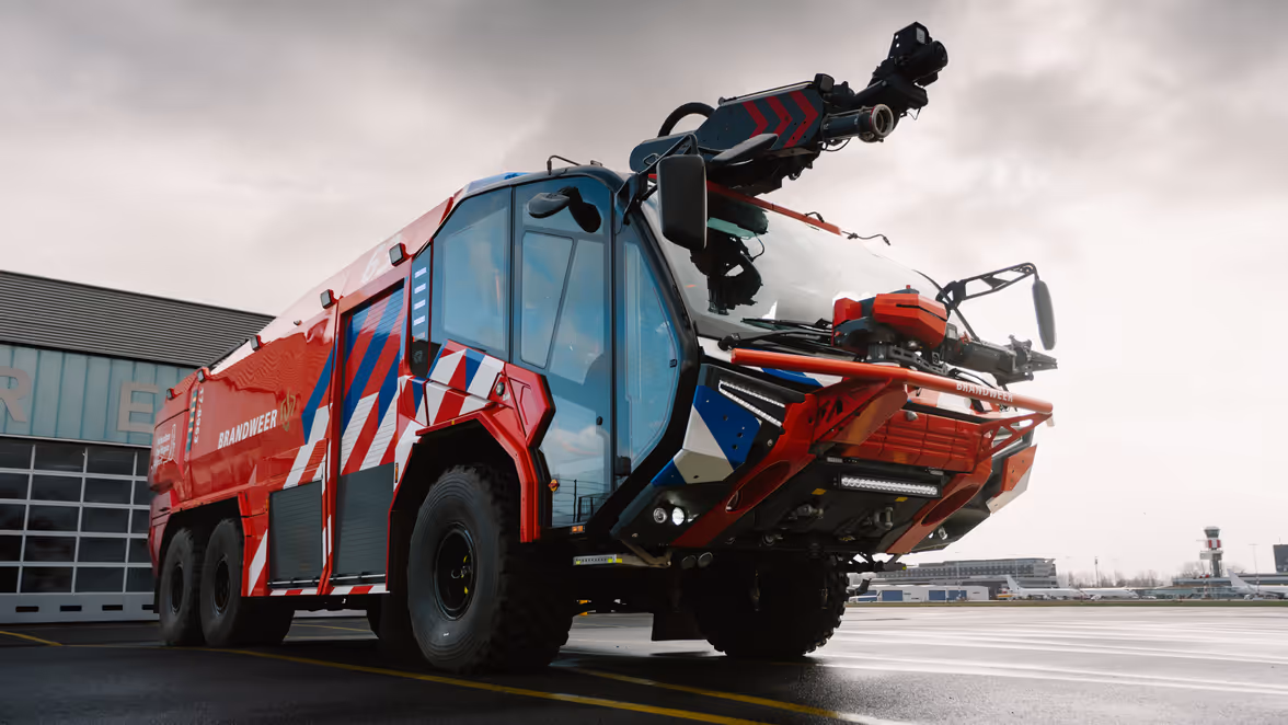 Brandweervoertuig geparkeerd op een luchthaven. 