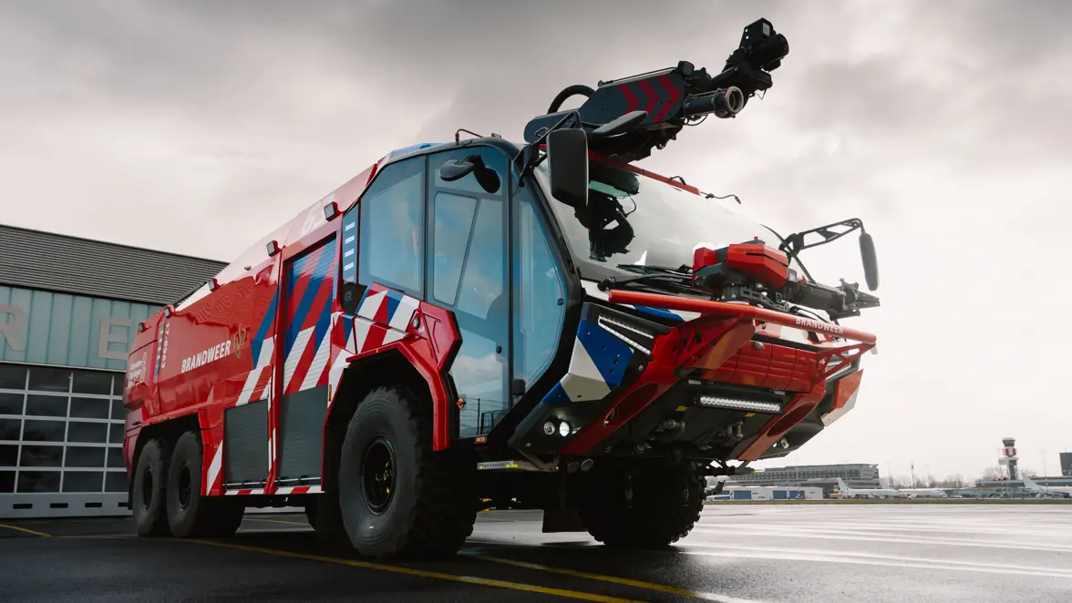 Brandweervoertuig geparkeerd op een luchthaven. 