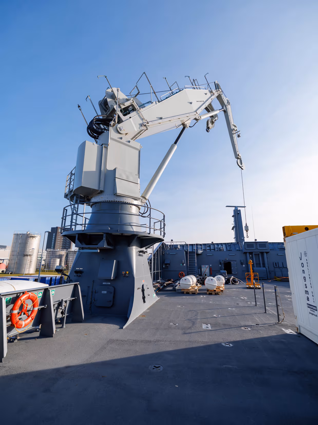 Een grijze kraan op het dek van het schip, een donkergrijze reddingsboot en het predicaat met daarop ‘Den Helder’.