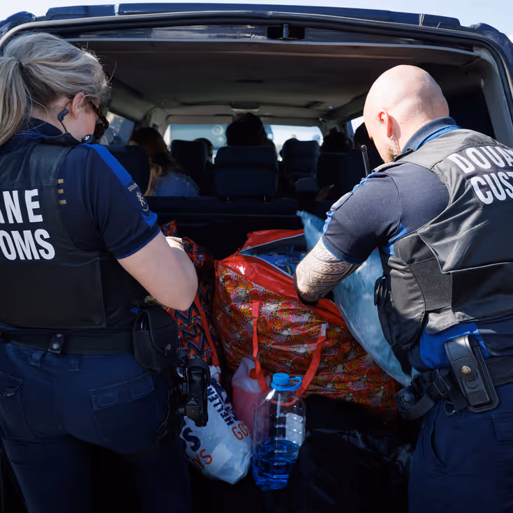 Douaniers onderzoeken de inhoud van een kofferbak.