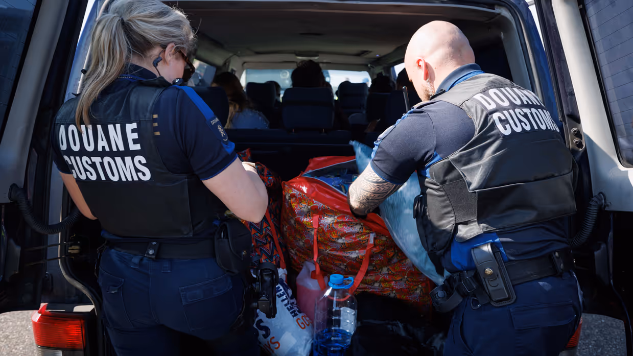 Douaniers onderzoeken de inhoud van een kofferbak.
