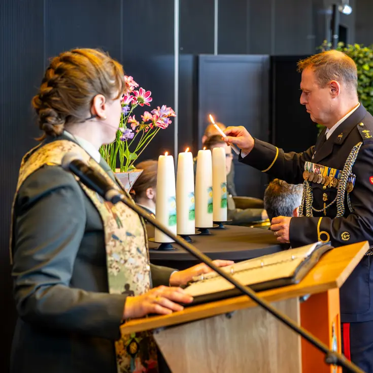 Onderdeelsadjudant Johan Nagel steekt een kaars aan. Dit is de derde in een rij van vier. De laatste brandt nog niet. 