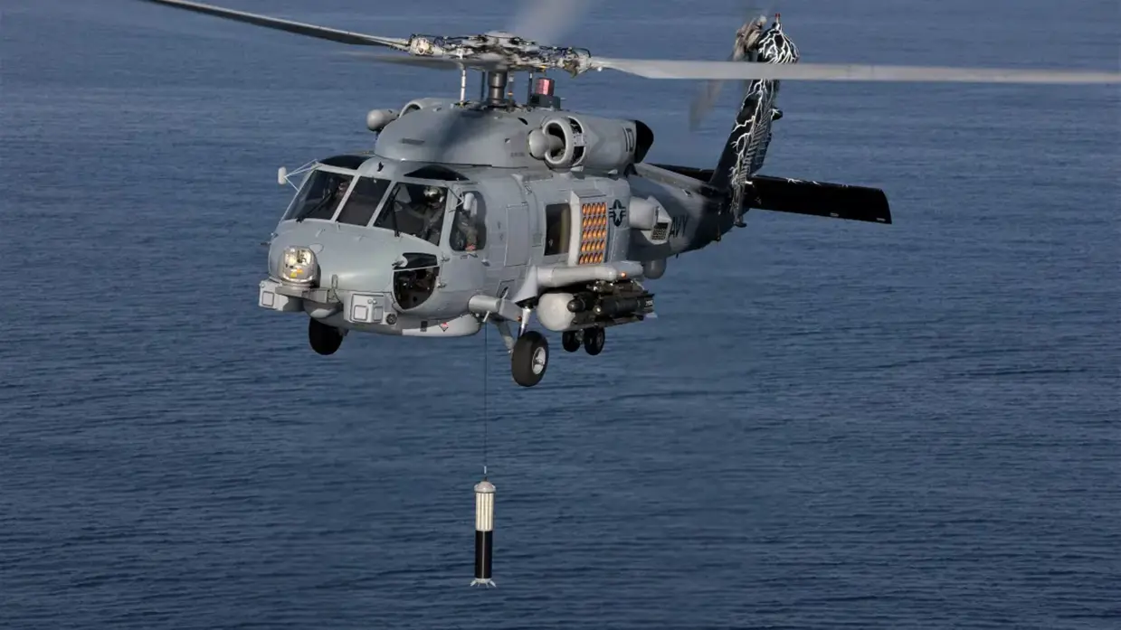 Een helikopter vliegt boven een kalme zee en laat een projectiel zakken aan een touw.