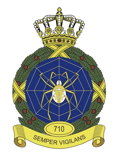 Kleurenfoto van een embleem met een spin in een web en een lauwerkrans eromheen.