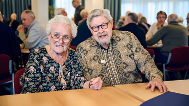 Een vrouw en een man lachen en zitten aan een tafel.