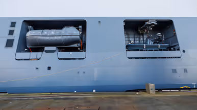 Een grijze kraan op het dek van het schip, een donkergrijze reddingsboot en het predicaat met daarop ‘Den Helder’.