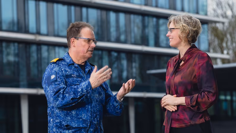 Commandeur Flos in blauw gevechtspak in gesprek met Carine van Bentum. 