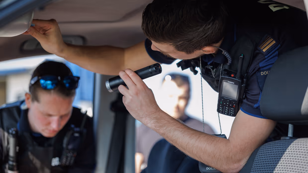 Douaniers onderzoeken een auto van binnen.