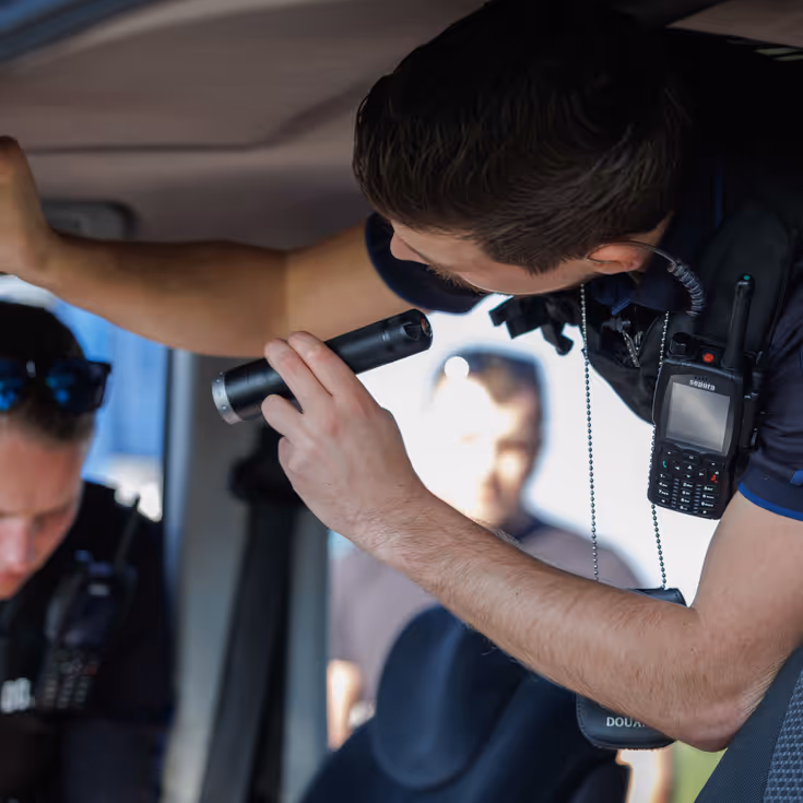 Douaniers onderzoeken een auto van binnen.