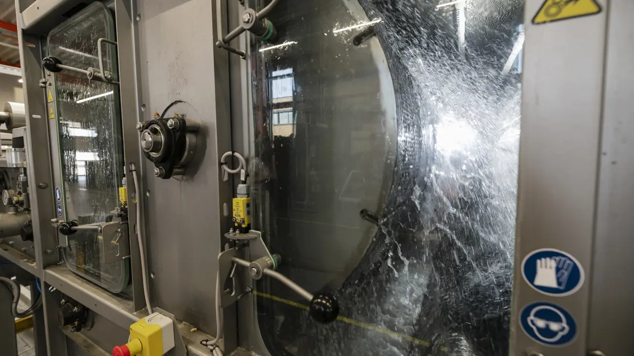 Water klotst op en neer in industriële wasmachine voor stoffen.